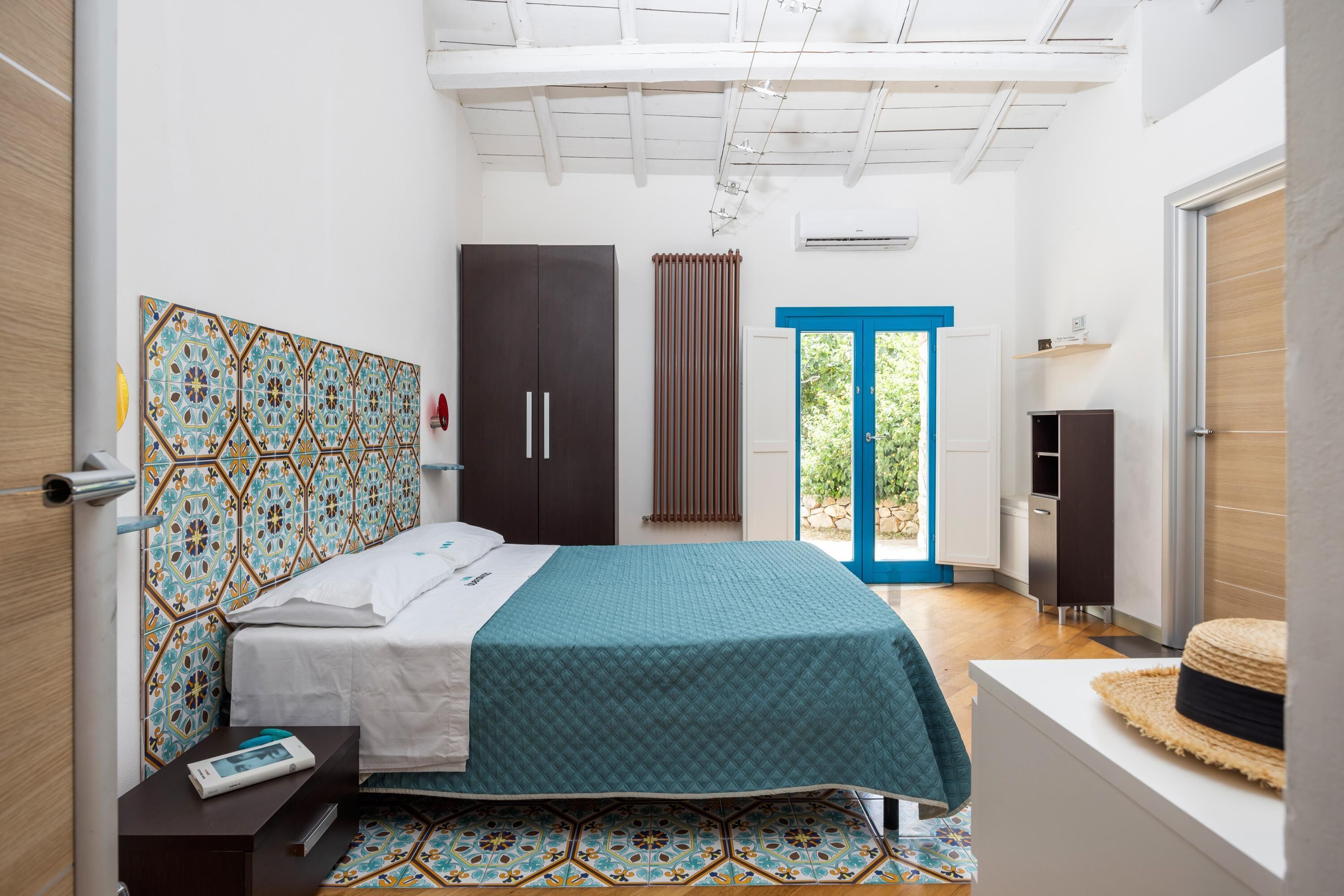Une chambre à coucher comprenant un lit, une table de chevet, une armoire, une fenêtre avec des rideaux et une vue sur l’extérieur.
