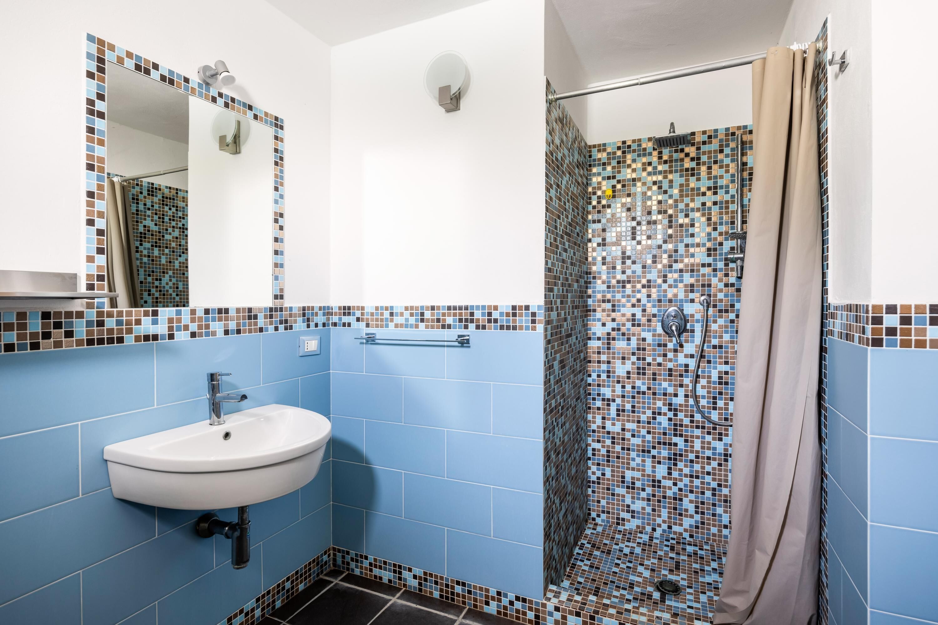 Un baño con lavamanos, espejo y zona de ducha.