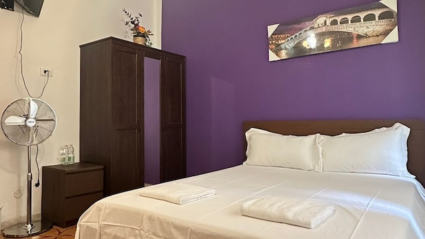 A bedroom with a bed, a TV, a fan, and a cabinet. - VENICE NIGHT 25 DOUBLE ROOM C (Mestre)