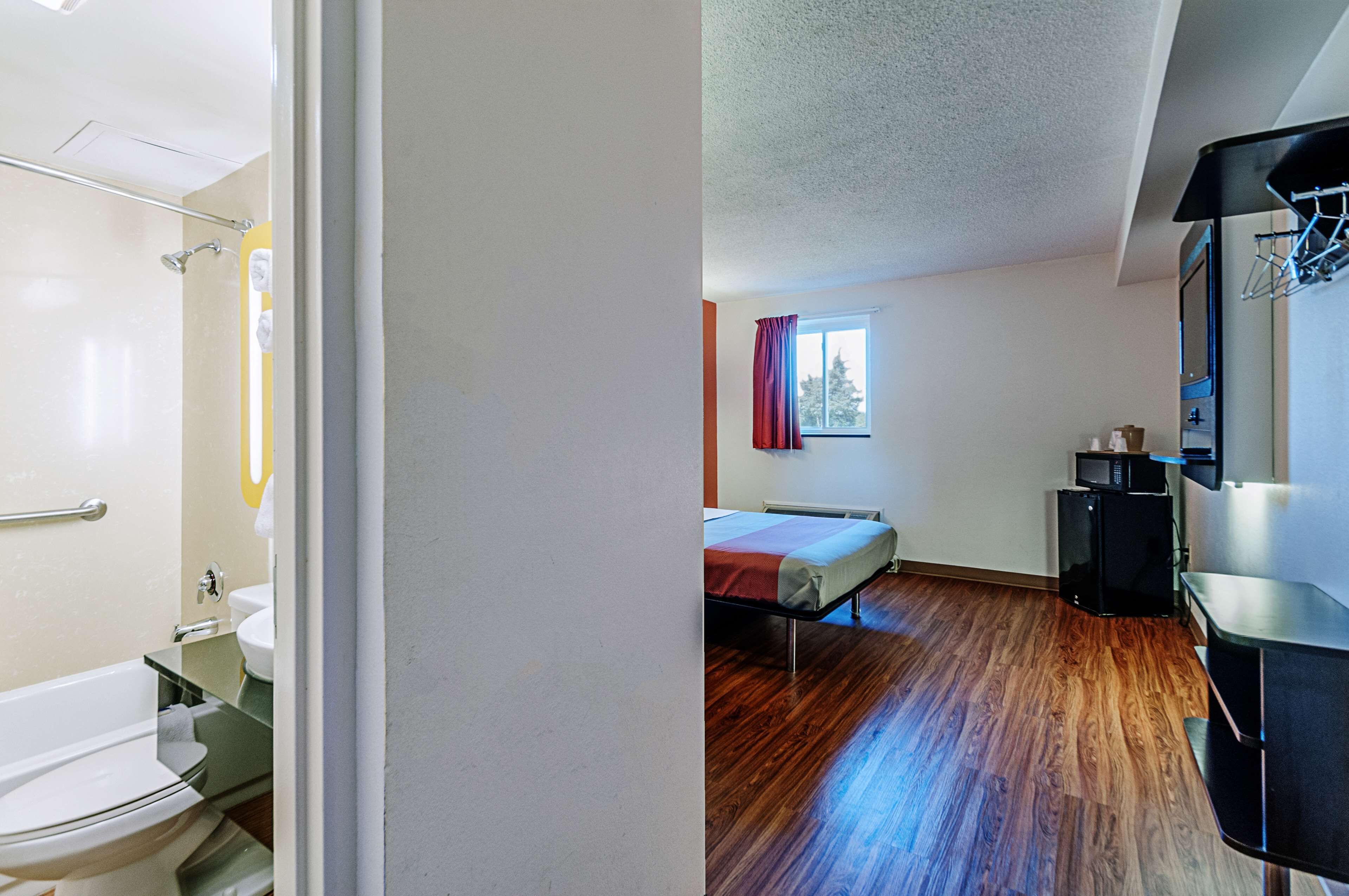 A room with a bed, a small window, a microwave, and a sink.