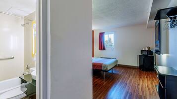 A room with a bed, a small window, a microwave, and a sink.