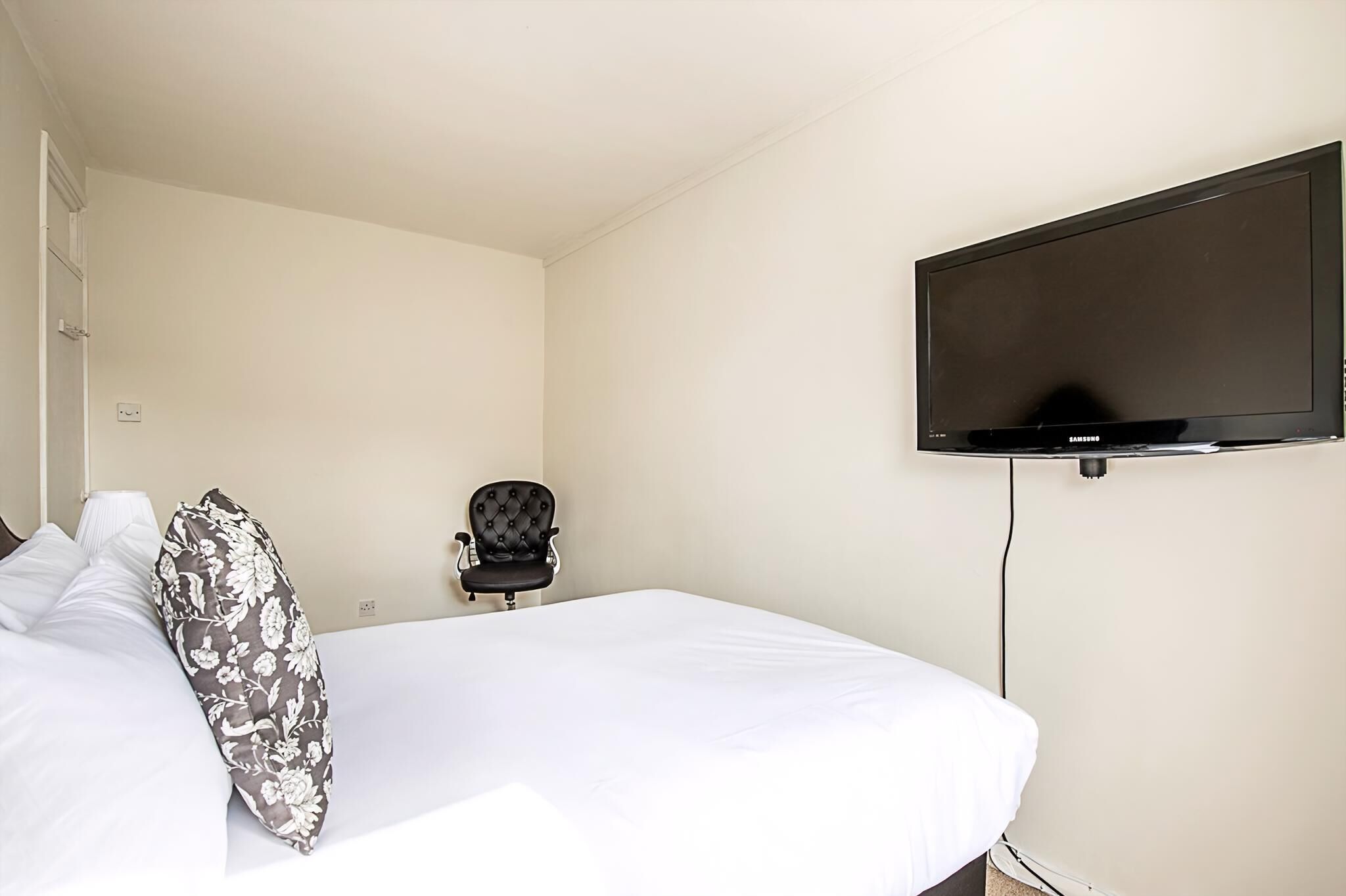 Ein Hotelzimmer mit einem Bett, einem Sessel und einem Wandfernseher.