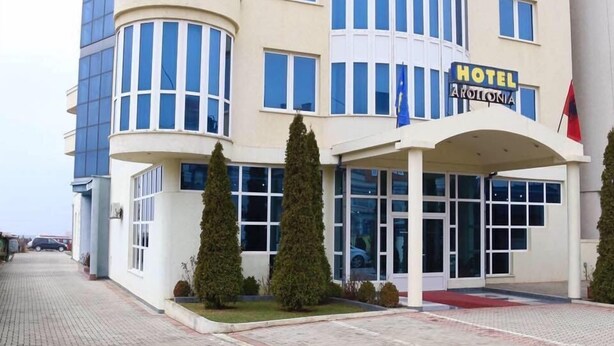 A hotel with a curved facade, multiple windows, and a prominent entrance with a red carpet. - Hotel Apollonia (Pristina)