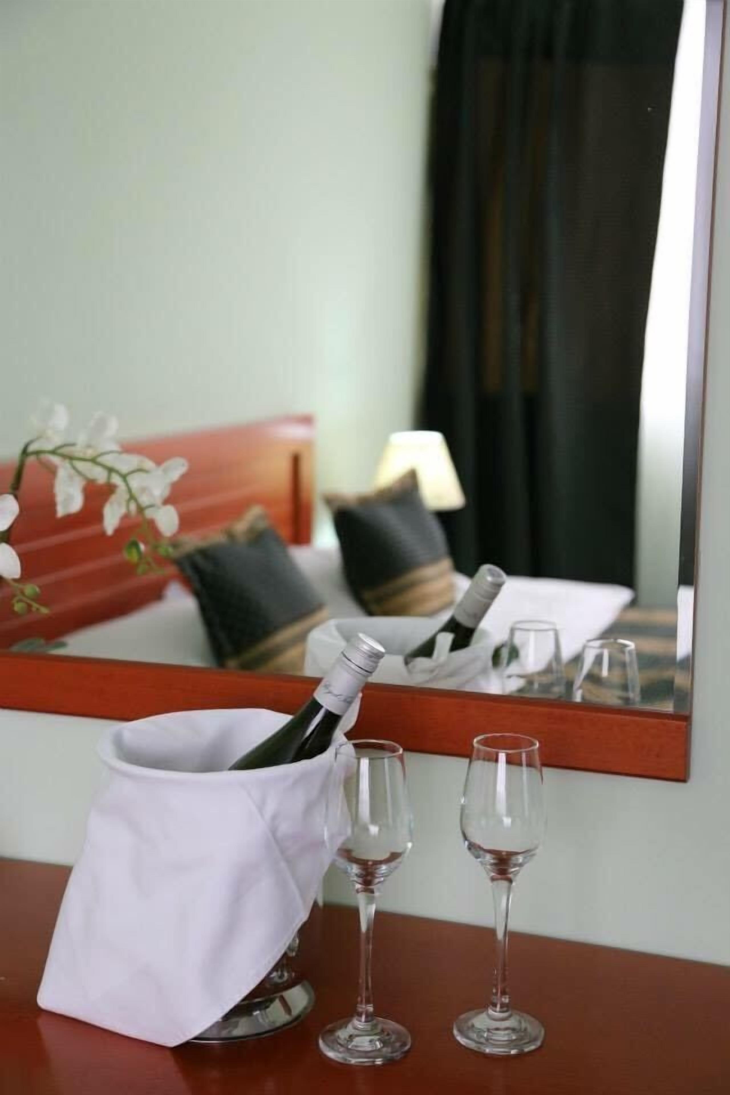 Una habitación de hotel con una mesita de noche de madera, una botella de champán y dos copas de vino vacías.