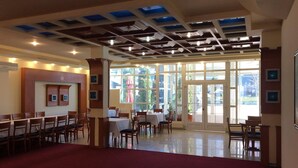 A spacious room with a high ceiling, large windows, and a red carpet. - Hotel Apollonia (Pristina)