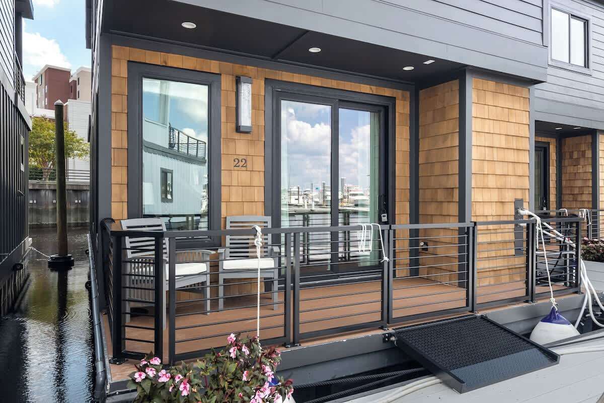 A modern building with a wooden facade, large windows, and a balcony with seating.