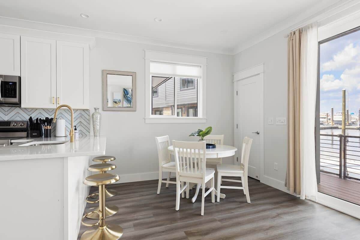 Una cocina moderna con armarios blancos, microondas integrado y una zona con taburete de bar.