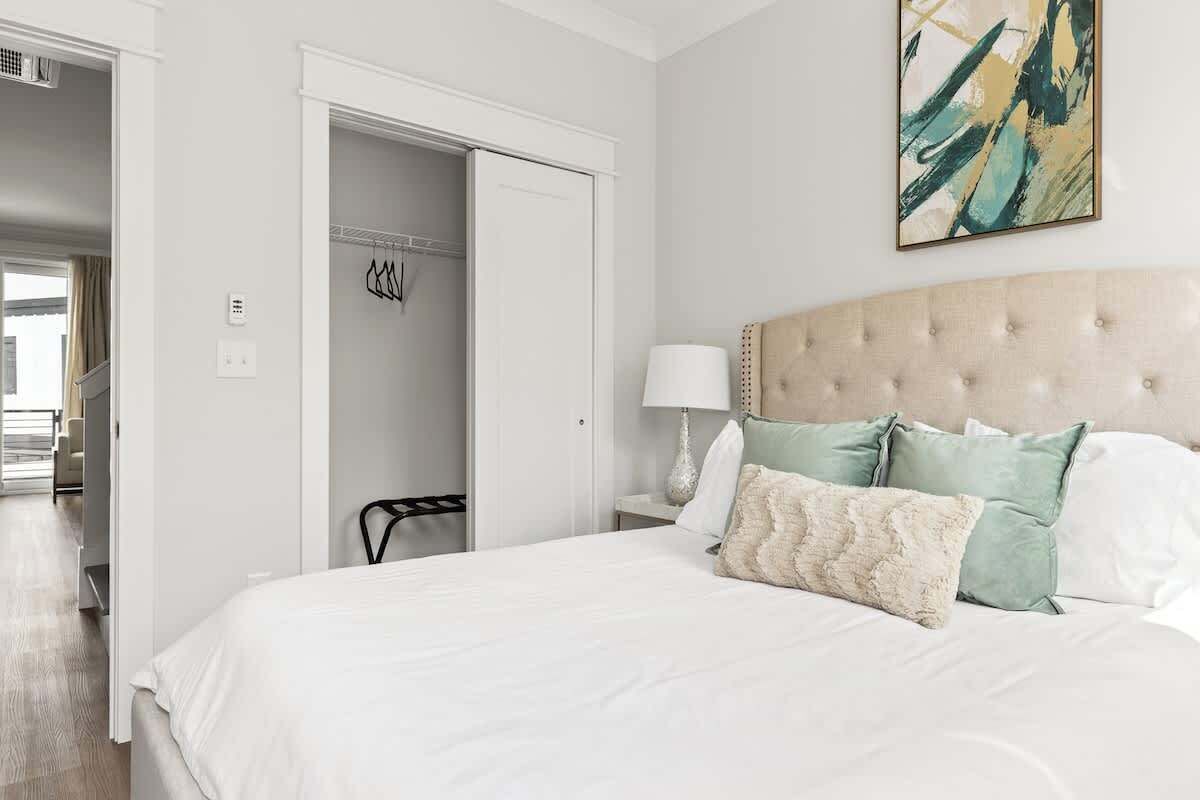 Quarto com uma cama grande, cabeceira, abajur e um quadro na parede.