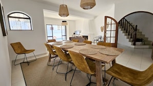 Ein Essbereich mit Holztisch, braunen Stühlen, gewobenen Tischsets und hängenden Korbtischen.