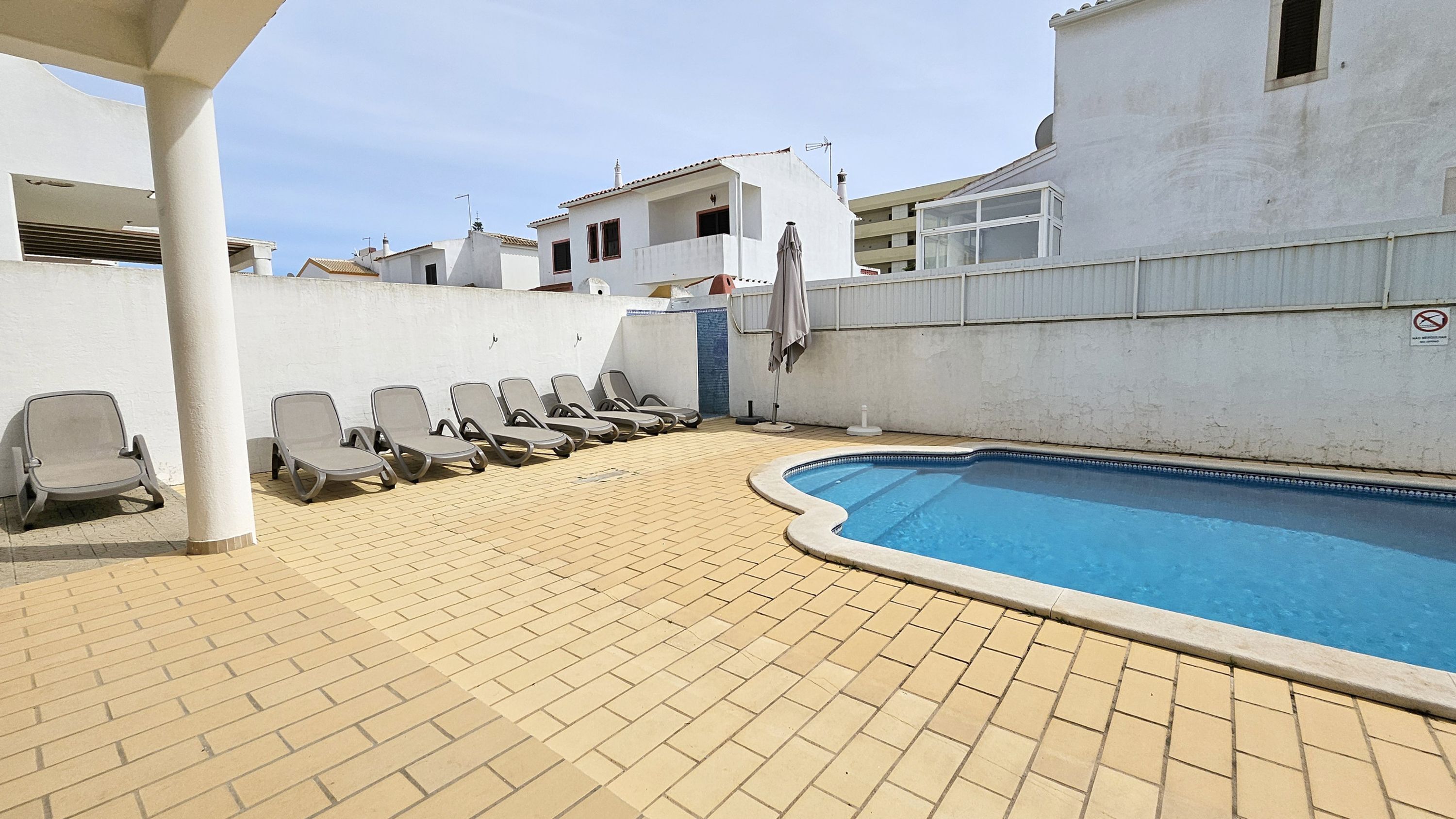 Une piscine avec des chaises longues et une terrasse carrelée.