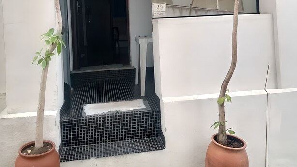 Un acceso a un espacio al aire libre techado, con una pequeña mesa y una planta en maceta.