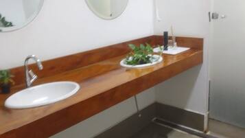 Un baño con lavamanos blanco, tocador de madera, espejo y alfombra verde en el suelo.