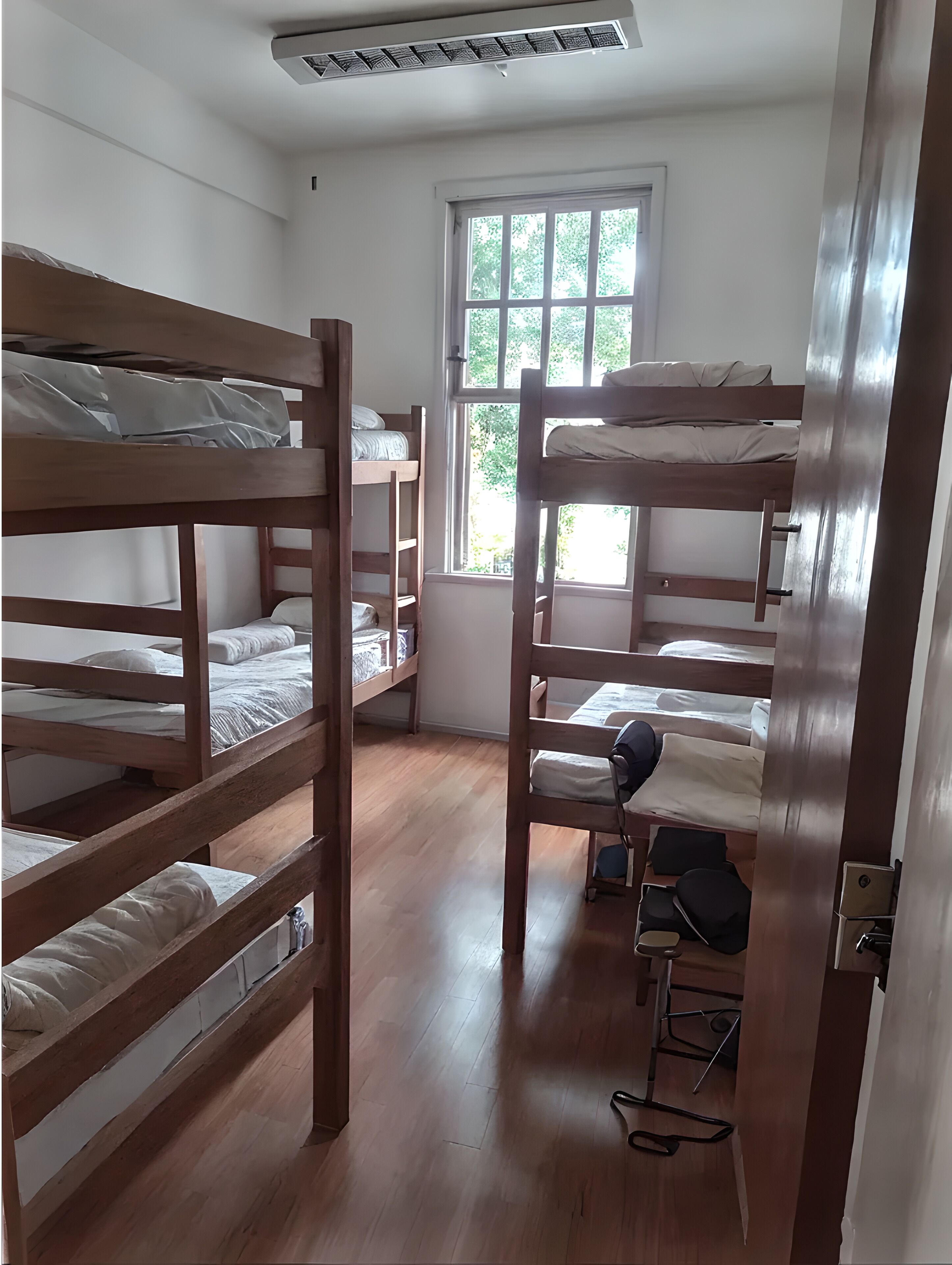 A room with bunk beds, a window, and a desk with a chair.