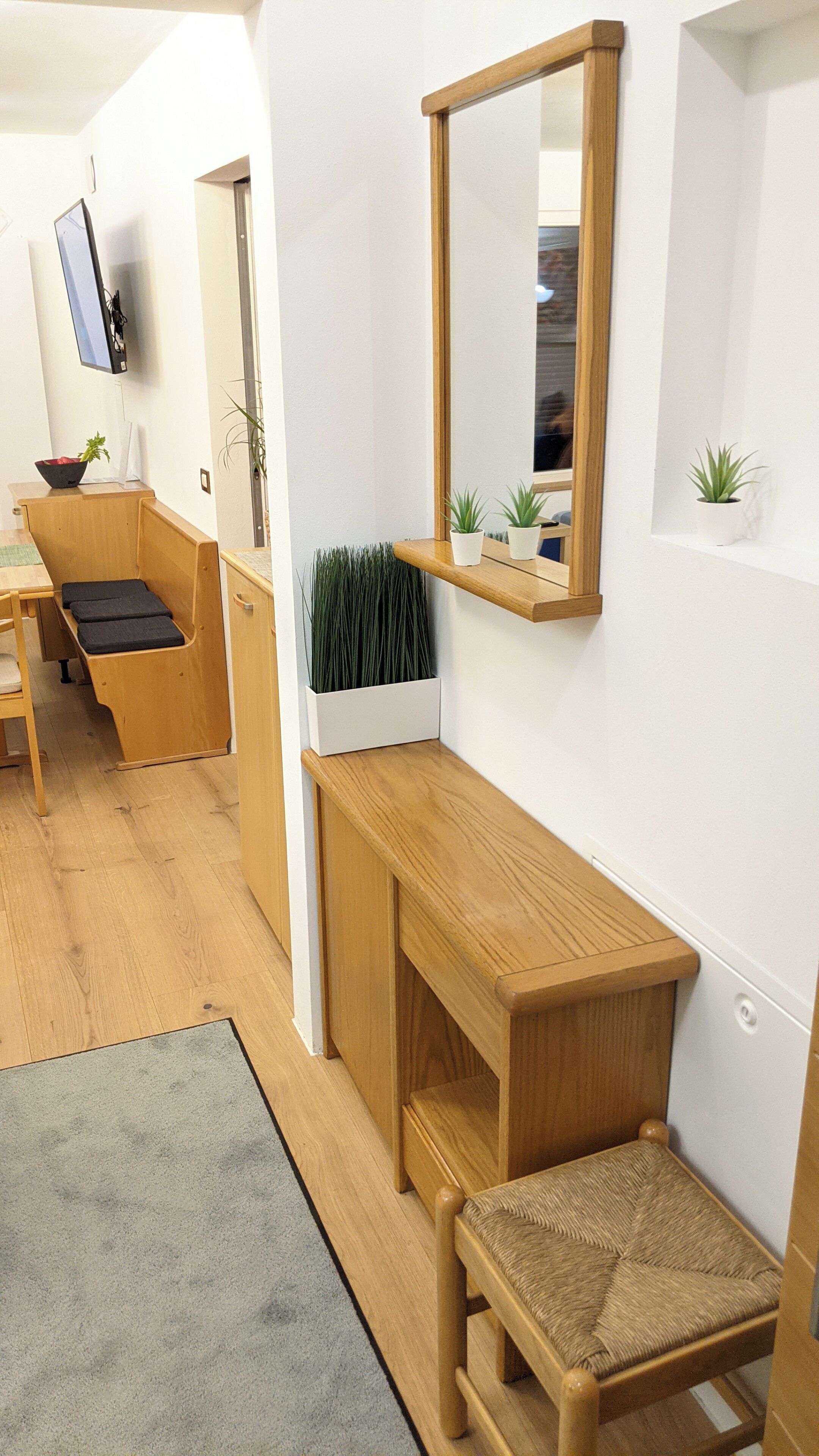A modern, minimalist room with a wooden bench, a small table, and a mirror on the wall.