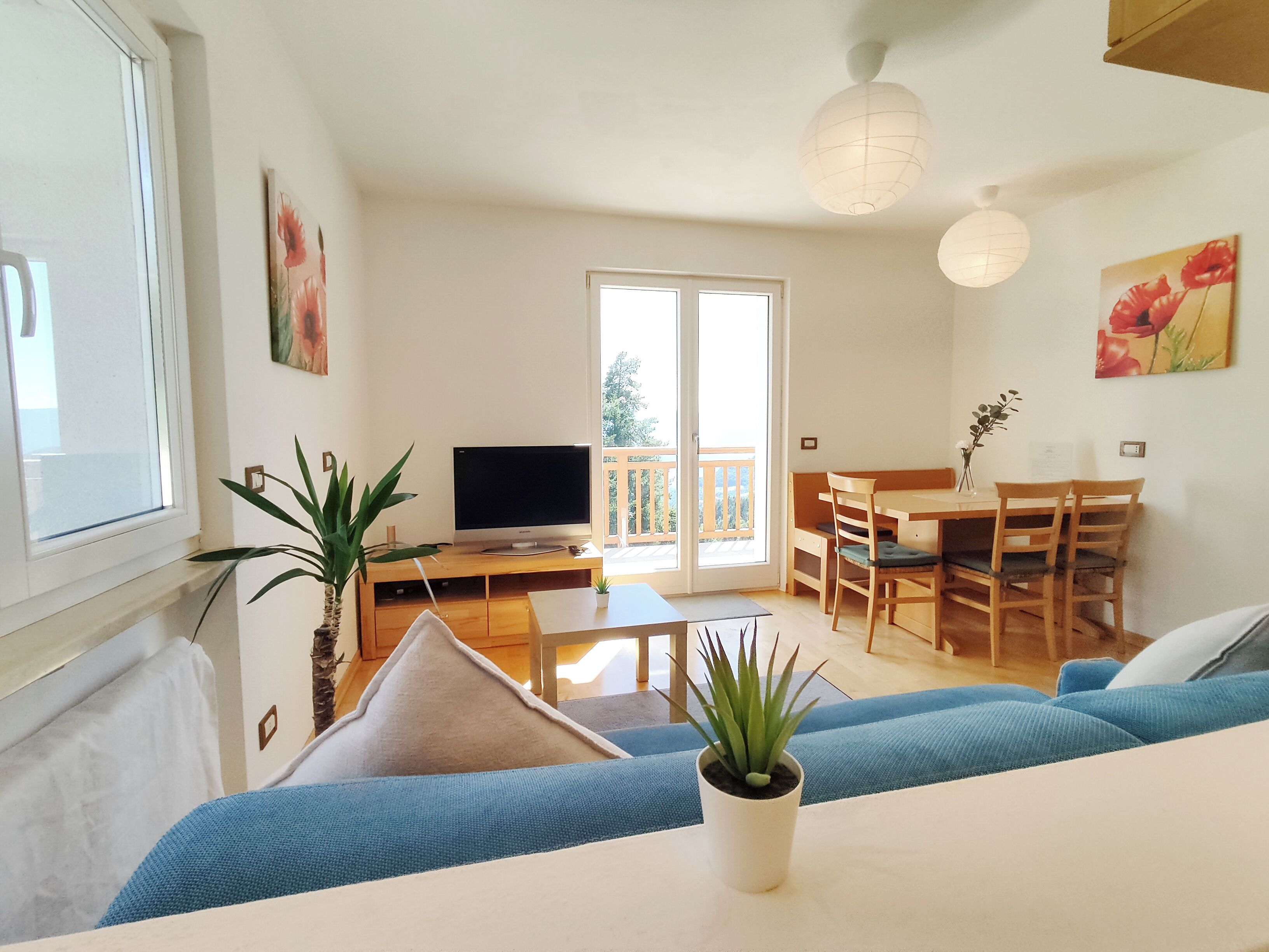 Un salon équipé d’un téléviseur, d’un canapé, d’une table à manger, de chaises et d’un balcon.