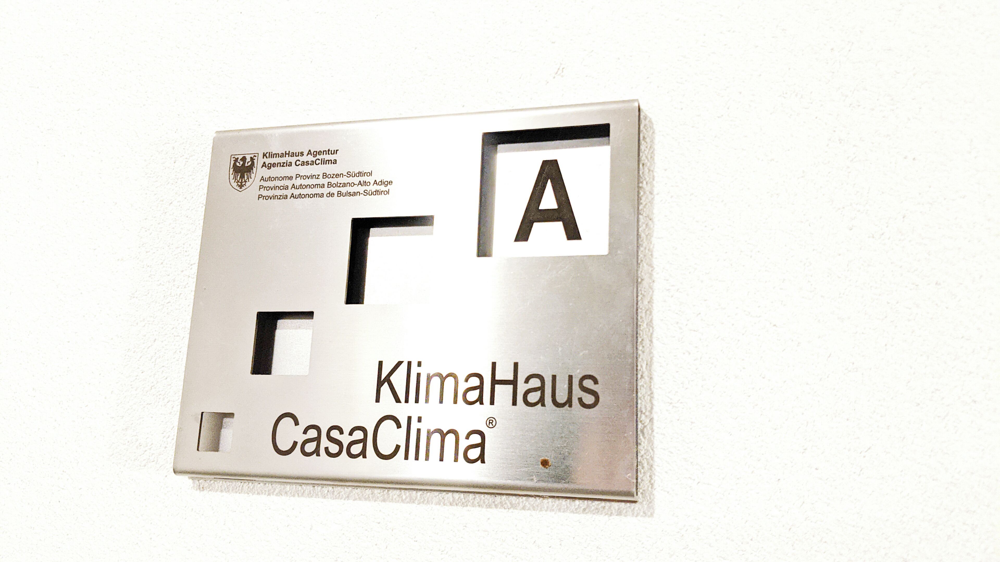 A metallic plaque with the text "KlimaHaus Agencia CasaClima" and a logo.