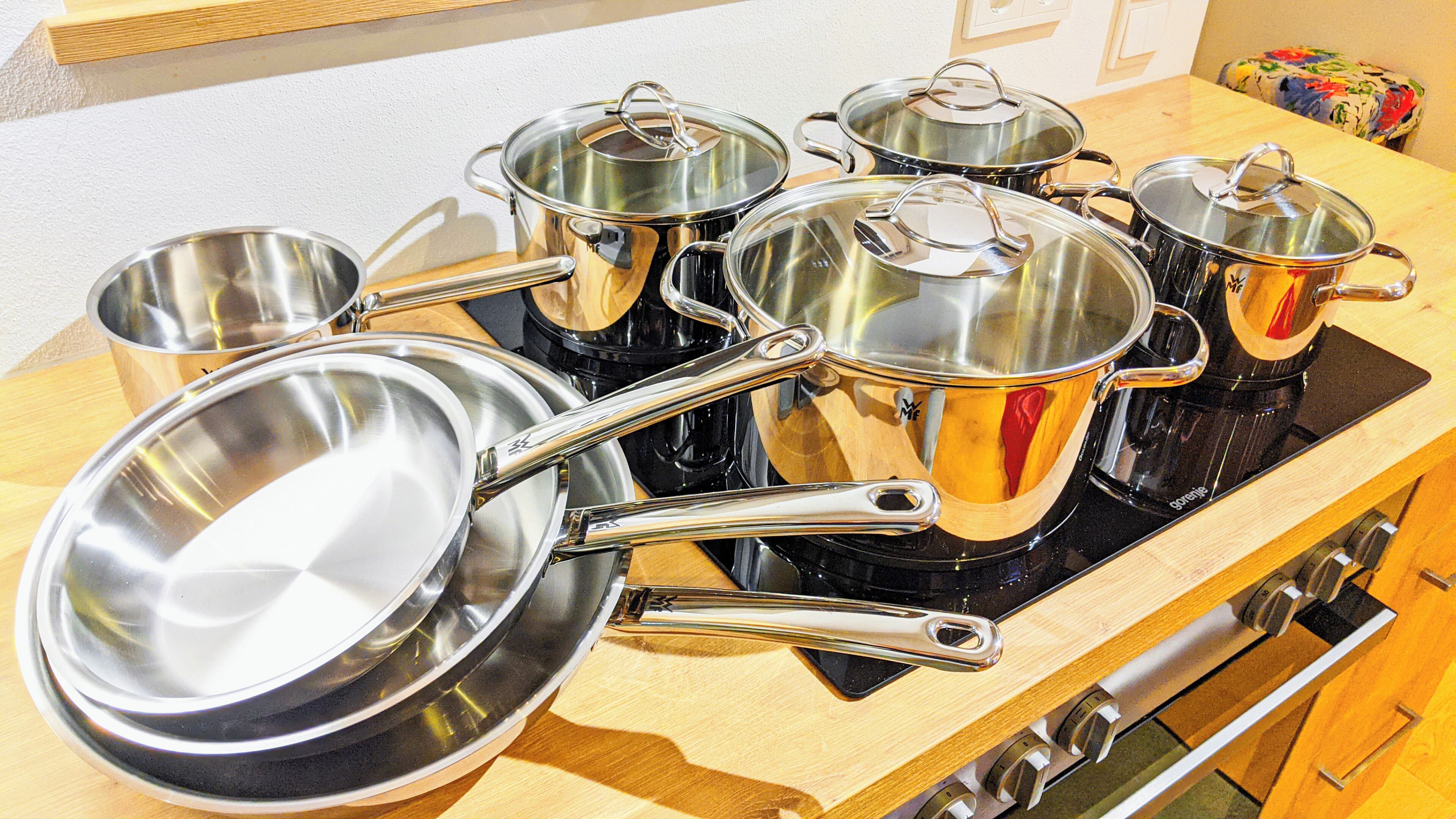 Een keuken met roestvrijstalen kookgerei op een fornuis.
