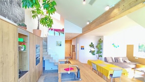 A modern interior with a staircase, wooden floors, a dining area, and a seating area. - Vidora Apartments (Renon)