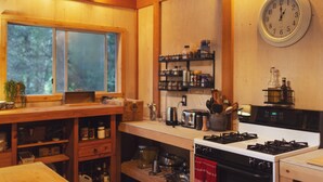 Una cocina con armarios de madera, una estufa, un reloj y varios utensilios de cocina sobre la encimera.
