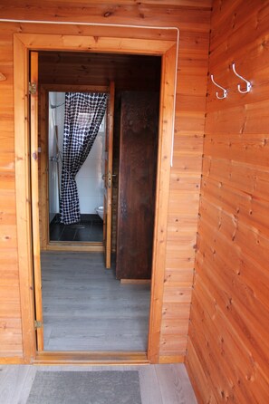 A wooden cabin interior with a visible bathroom featuring a shower curtain and a toilet. - Lofoten Camp Storfjord (Vestvågøy)