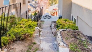 A narrow pathway leading to a building with a view of mountains in the distance. - Legal Lakeview 2-bed 2-bath Entire Suite (Kelowna)