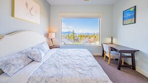 A bedroom with a large window, a bed, a desk, and a chair. - Legal Lakeview 2-bed 2-bath Entire Suite (Kelowna)