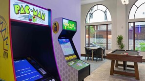 Une table de billard, des jeux d’arcade et une table de snooker dans une pièce dotée de grandes fenêtres.