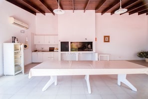 A spacious kitchen with white cabinets, a large table, and a built-in oven. - Oceana Suites Palm Beach (Punta del Este)