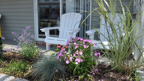 Une chaise blanche se trouve devant une maison qui a un jardin.