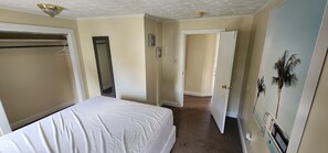 A hotel room with a bed, a wardrobe, a door leading to another room, and a wall with a palm tree painting. - 5 Seaview Ave (Old Orchard Beach)
