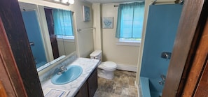 A bathroom with a blue sink, toilet, and a window with curtains. - 5 Seaview Ave (Old Orchard Beach)