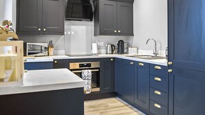A modern kitchen with dark cabinets, stainless steel appliances, and a blue accent wall.