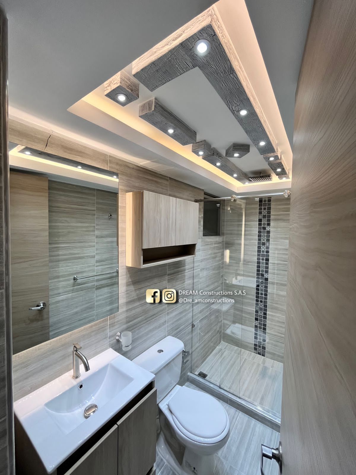 A modern bathroom with a double sink, toilet, and a glass shower enclosure.