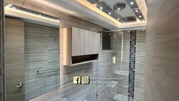 A modern bathroom with a double sink, toilet, and a glass shower enclosure.