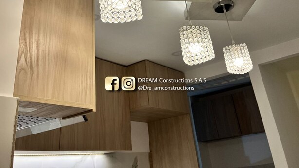 A modern kitchen with wooden cabinets, a marble countertop, and pendant lights with a unique design. - Hermoso Apatamento CON Aire Neiva (Neiva)