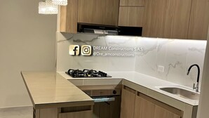A modern kitchen with wooden cabinets, a built-in stove, and a marble backsplash. - Hermoso Apatamento CON Aire Neiva (Neiva)