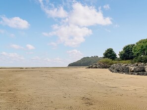 A beach with a castle on a hill, sandy terrain, and a clear sky.