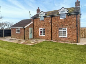 A two-story brick house with a front door, a small porch, and a grassy yard. - The Lodge at Owstwick Hall (Owstwick, near Roos)