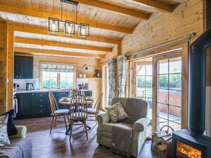 A cozy cabin interior with a dining area, a sofa, and a fireplace. - Stable Lodge at Greenacre (Bromyard)