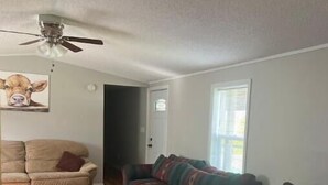 A living room with a wooden floor, a beige sofa, a multicolored sofa, and a ceiling fan. - Private Shawnee National Forest Retreat , Near Garden of the Gods (Elizabethtown)