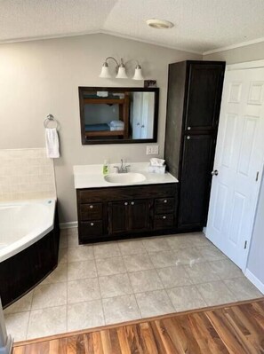 A bathroom with a bathtub, a sink, a mirror, and dark wooden cabinets.