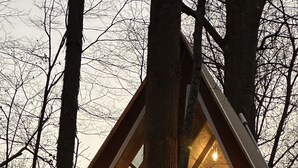 En træhytte med et trekantet tag, store vinduer og en balkon.