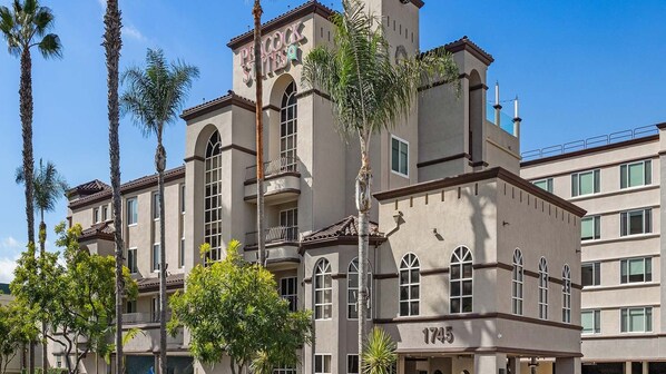 A multi-story hotel with a prominent tower, arched windows, and a balcony.