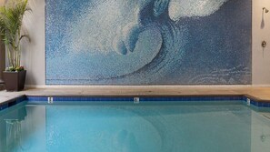 A swimming pool with a mosaic wall in the background.