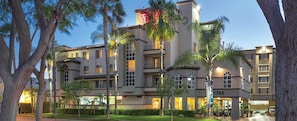 A multi-story hotel with balconies, a well-maintained lawn, and a clear sky. - 2br Family Fun Near Disney & Knotts Berry Farm (Anaheim)