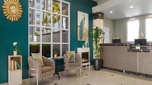 A reception area with a fireplace, two armchairs, a large window, and a reception desk.