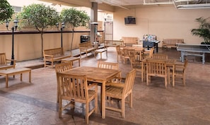 A covered outdoor seating area with wooden tables and chairs, a ping pong table, and a vending machine. - 2br Family Fun Near Disney & Knotts Berry Farm (Anaheim)