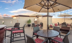 An outdoor patio area with wicker furniture, round tables, and large umbrellas. - 2br Family Fun Near Disney & Knotts Berry Farm (Anaheim)
