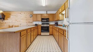 Eine Küche mit Holzausstattung, einer Mikrowelle, einem Backofen und einem Kühlschrank.