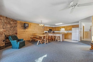 A spacious living area with a stone fireplace, wooden dining table, and a cozy seating arrangement.